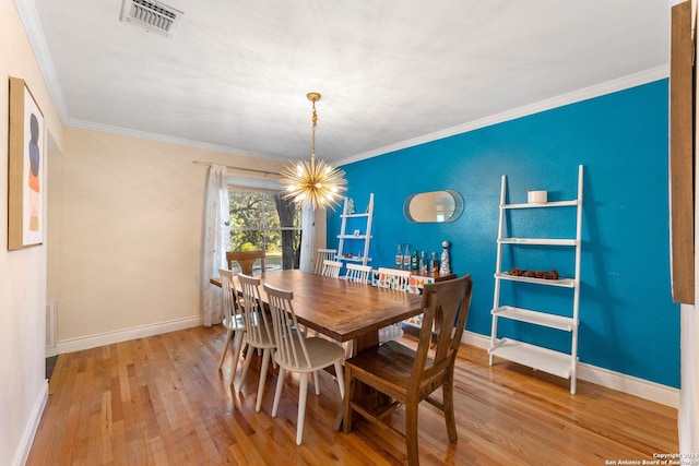 dining room with an inviting chandelier, ornamental molding, and light hardwood / wood-style flooring