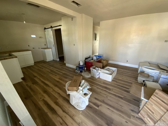 living room with a barn door, dark hardwood / wood-style flooring, and sink