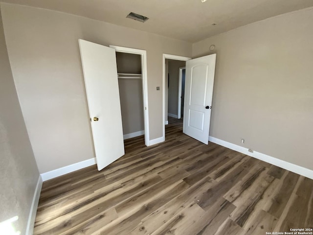 unfurnished bedroom with dark wood-type flooring and a closet