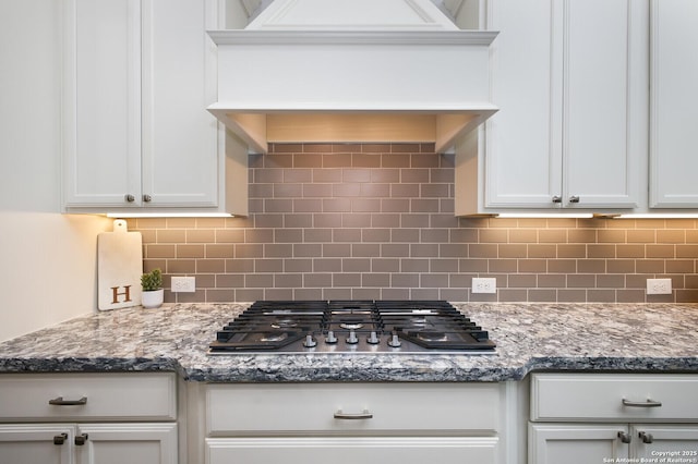 kitchen featuring decorative backsplash, stainless steel gas stovetop, and white cabinetry