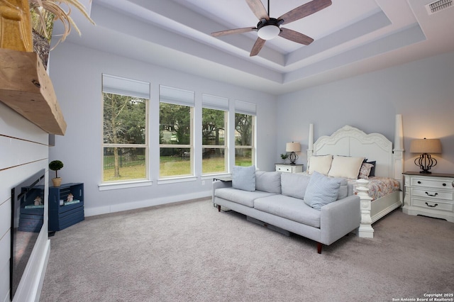 carpeted bedroom featuring ceiling fan and a raised ceiling