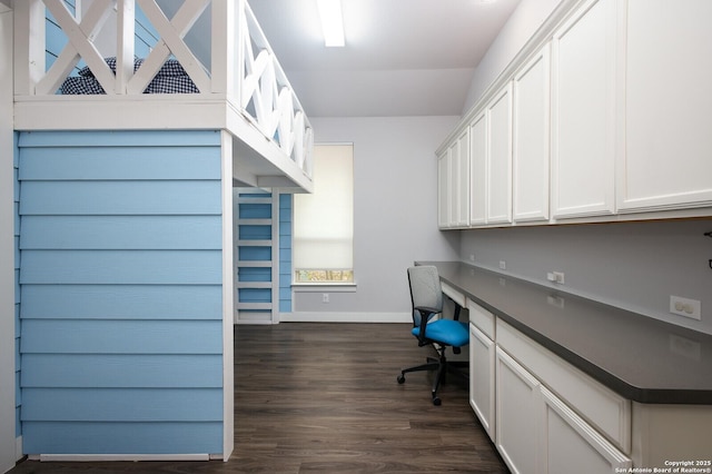 home office with built in desk and dark hardwood / wood-style floors