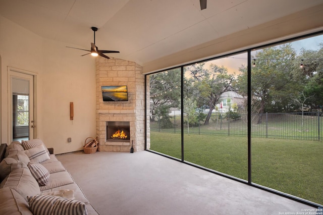 unfurnished living room featuring ceiling fan, lofted ceiling, a fireplace, and plenty of natural light