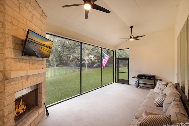 sunroom / solarium featuring ceiling fan, lofted ceiling, and a stone fireplace