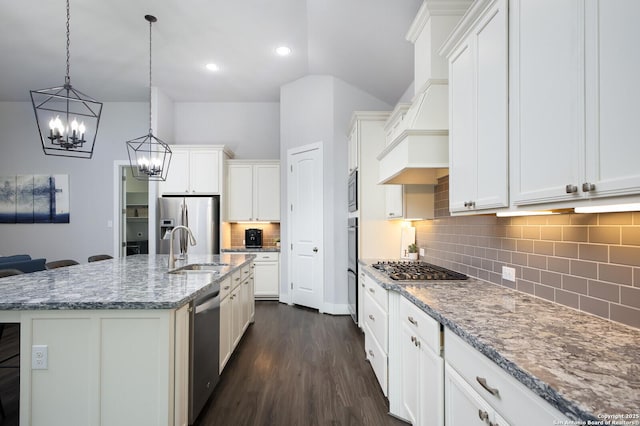 kitchen featuring decorative light fixtures, a center island with sink, sink, white cabinetry, and appliances with stainless steel finishes