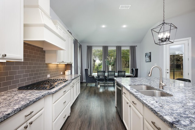 kitchen featuring stainless steel appliances, lofted ceiling, light stone counters, and sink