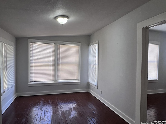 empty room featuring plenty of natural light, dark wood-type flooring, and a textured ceiling