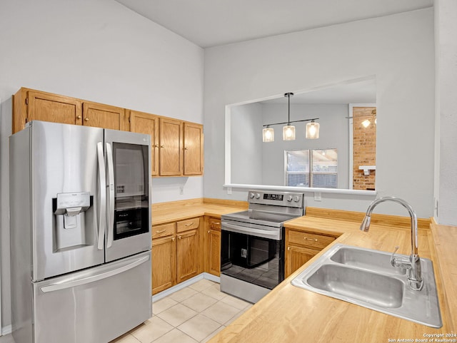 kitchen with wood counters, hanging light fixtures, sink, light tile patterned floors, and appliances with stainless steel finishes