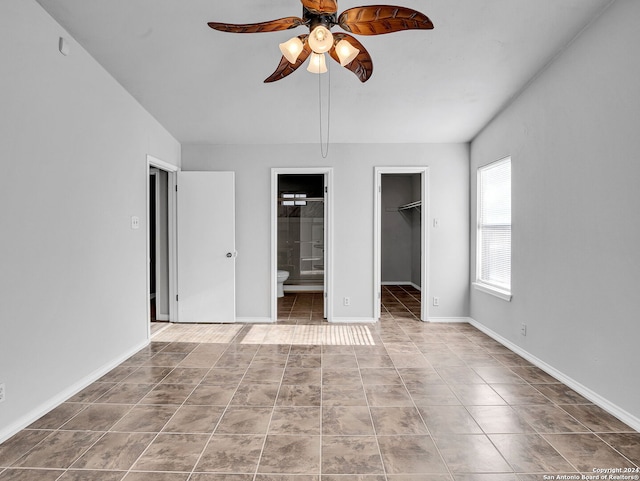 unfurnished bedroom featuring connected bathroom, a spacious closet, ceiling fan, a closet, and light tile patterned flooring