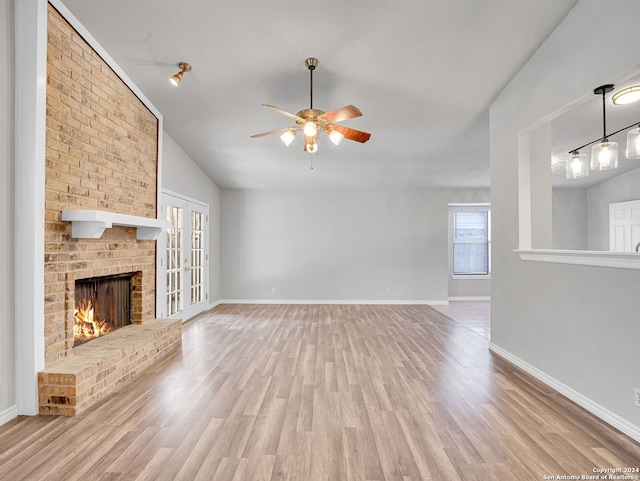 unfurnished living room with ceiling fan, french doors, light hardwood / wood-style flooring, lofted ceiling, and a fireplace