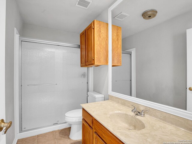 bathroom featuring tile patterned flooring, vanity, an enclosed shower, and toilet