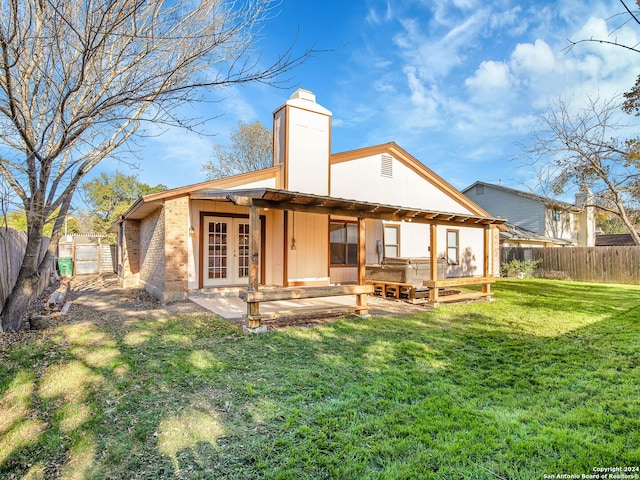 back of property with a patio area, a yard, and french doors