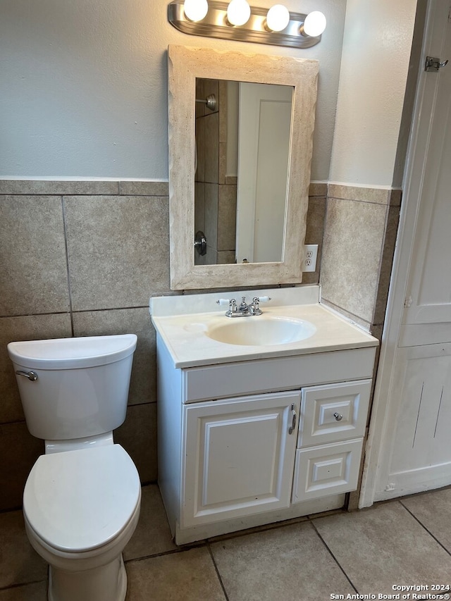 bathroom featuring vanity, toilet, and tile walls