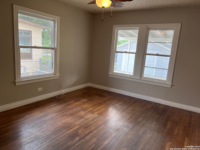 empty room with ceiling fan, dark hardwood / wood-style flooring, and a textured ceiling