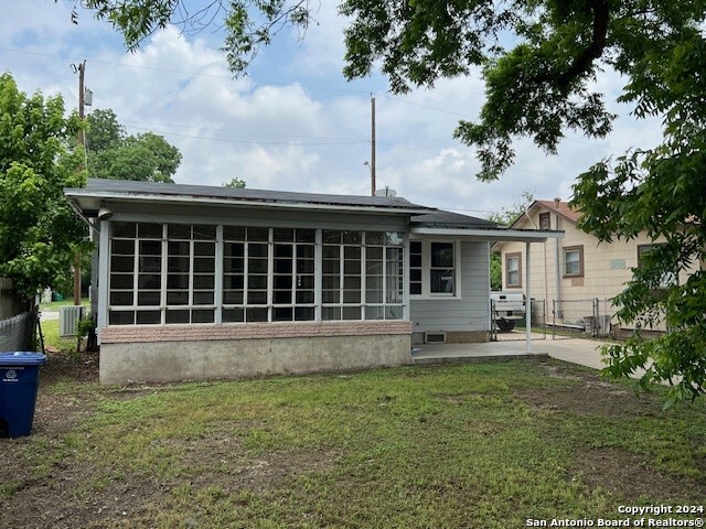 back of property featuring a sunroom and a lawn