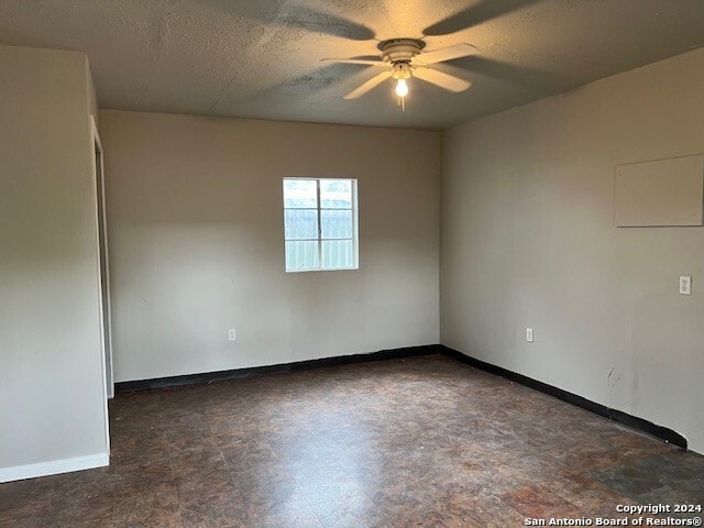 empty room with ceiling fan and a textured ceiling