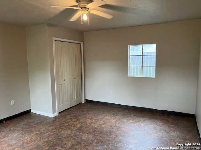 unfurnished bedroom featuring a textured ceiling, a closet, and ceiling fan