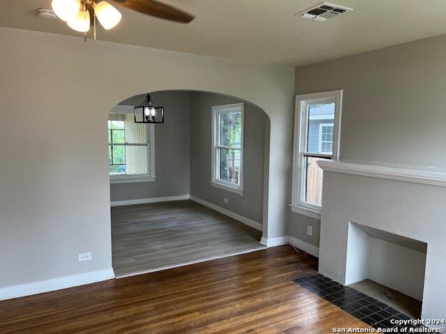 unfurnished dining area with ceiling fan with notable chandelier and dark hardwood / wood-style floors