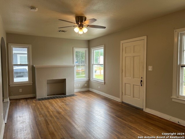 unfurnished living room featuring a textured ceiling, dark hardwood / wood-style floors, ceiling fan, and a fireplace