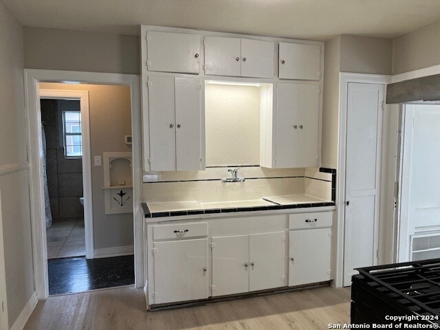 kitchen featuring tile countertops, white cabinetry, and light hardwood / wood-style flooring