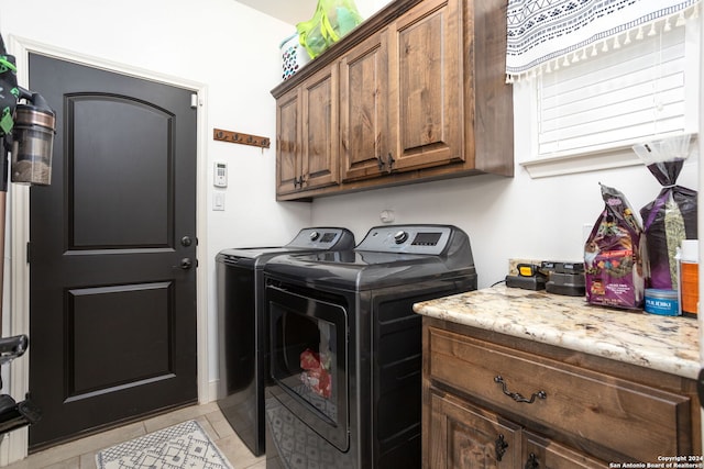 laundry room with cabinets, light tile patterned floors, and washing machine and clothes dryer