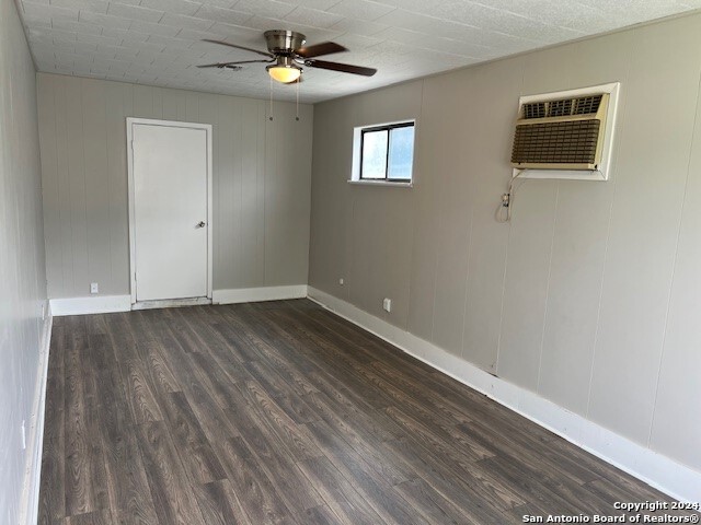 spare room featuring dark hardwood / wood-style floors, ceiling fan, and a wall mounted AC