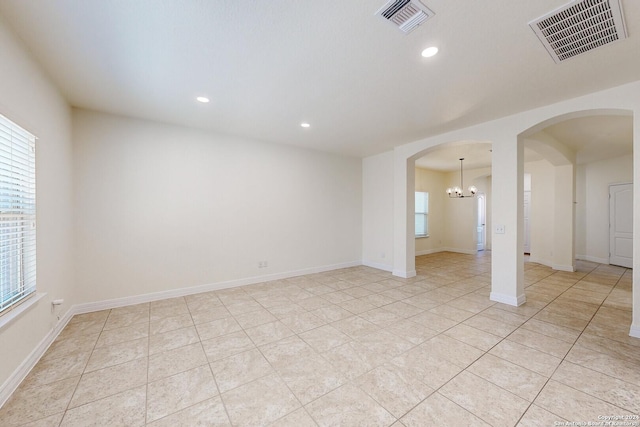 empty room featuring light tile patterned flooring and a chandelier