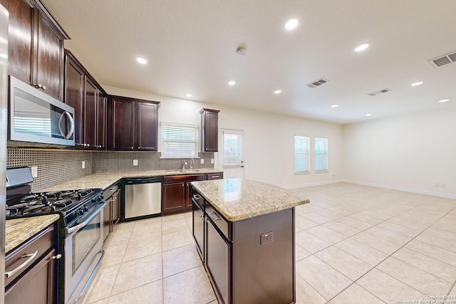 kitchen with a center island, light stone counters, sink, and appliances with stainless steel finishes