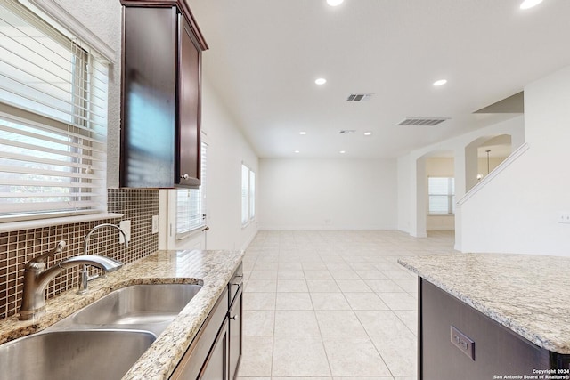 kitchen with decorative backsplash, light tile patterned flooring, light stone counters, and sink