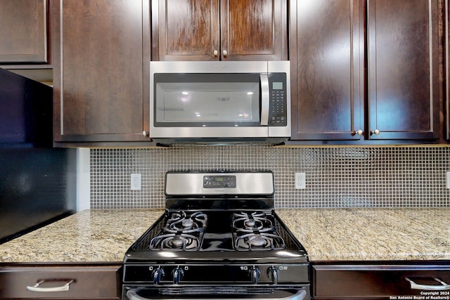 kitchen with backsplash, light stone countertops, dark brown cabinets, and stainless steel appliances