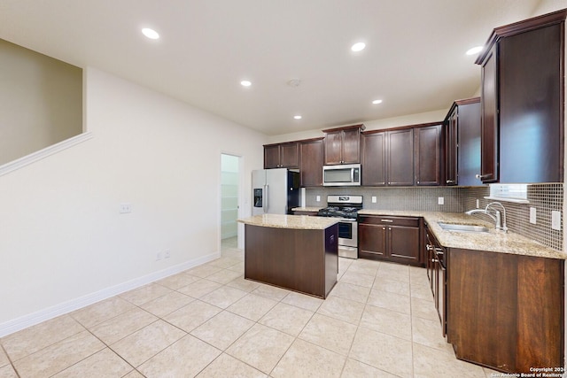 kitchen featuring sink, a center island, light stone counters, and appliances with stainless steel finishes