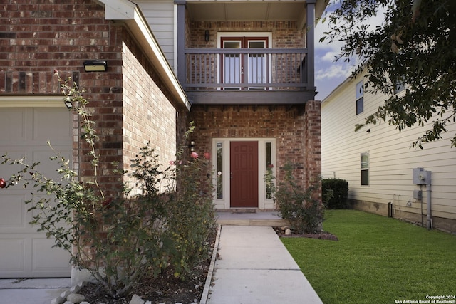 view of exterior entry with a yard and a balcony