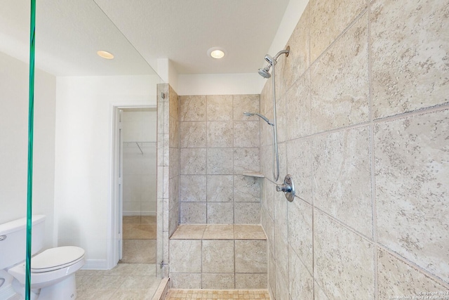 bathroom with a tile shower and toilet