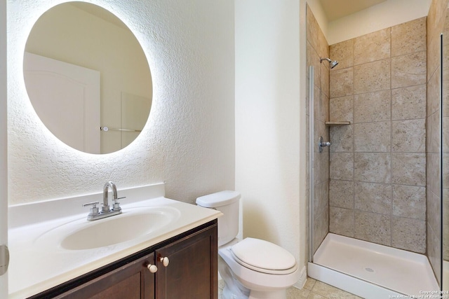 bathroom with tile patterned flooring, vanity, toilet, and tiled shower