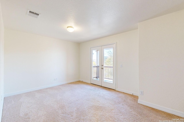 carpeted empty room with french doors and a textured ceiling