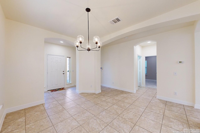 tiled spare room with a chandelier