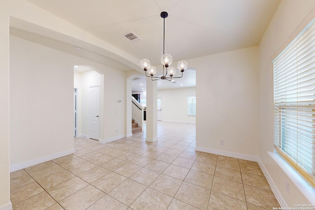 empty room featuring an inviting chandelier and light tile patterned flooring