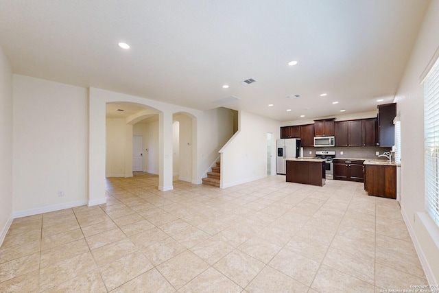 kitchen featuring tasteful backsplash, stainless steel appliances, sink, light tile patterned floors, and a center island