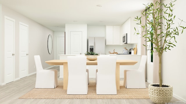 kitchen featuring white cabinetry, white refrigerator with ice dispenser, a breakfast bar area, and light hardwood / wood-style flooring