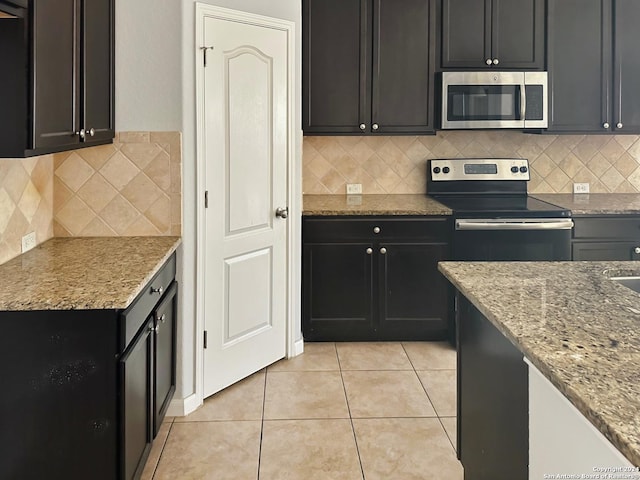 kitchen with decorative backsplash, light stone countertops, light tile patterned floors, and stainless steel appliances