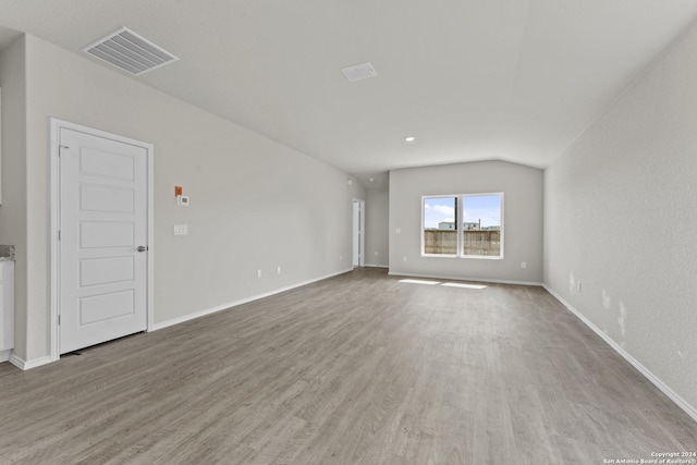 interior space with light wood-type flooring and vaulted ceiling