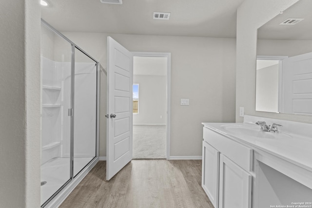 bathroom featuring wood-type flooring, vanity, and a shower with door