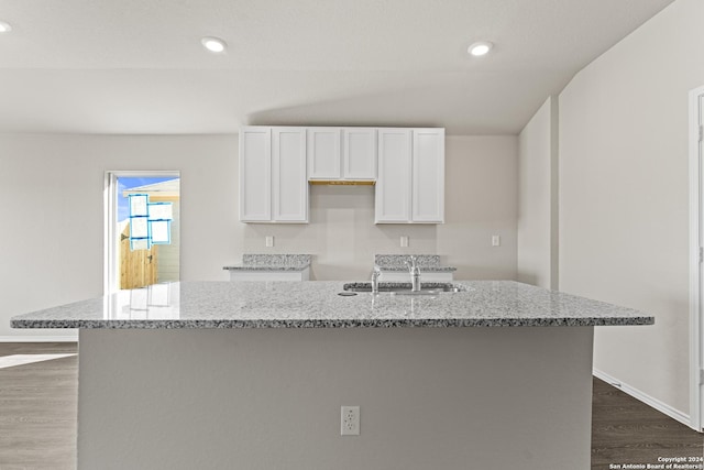 kitchen featuring light stone countertops, dark wood-type flooring, sink, a center island with sink, and white cabinetry