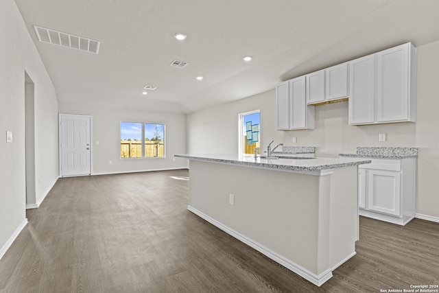 kitchen featuring sink, light stone counters, dark hardwood / wood-style floors, a kitchen island with sink, and white cabinets