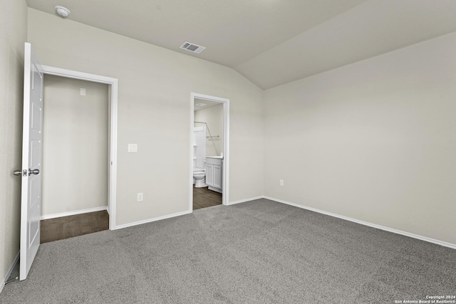 unfurnished bedroom featuring dark colored carpet, ensuite bath, and lofted ceiling