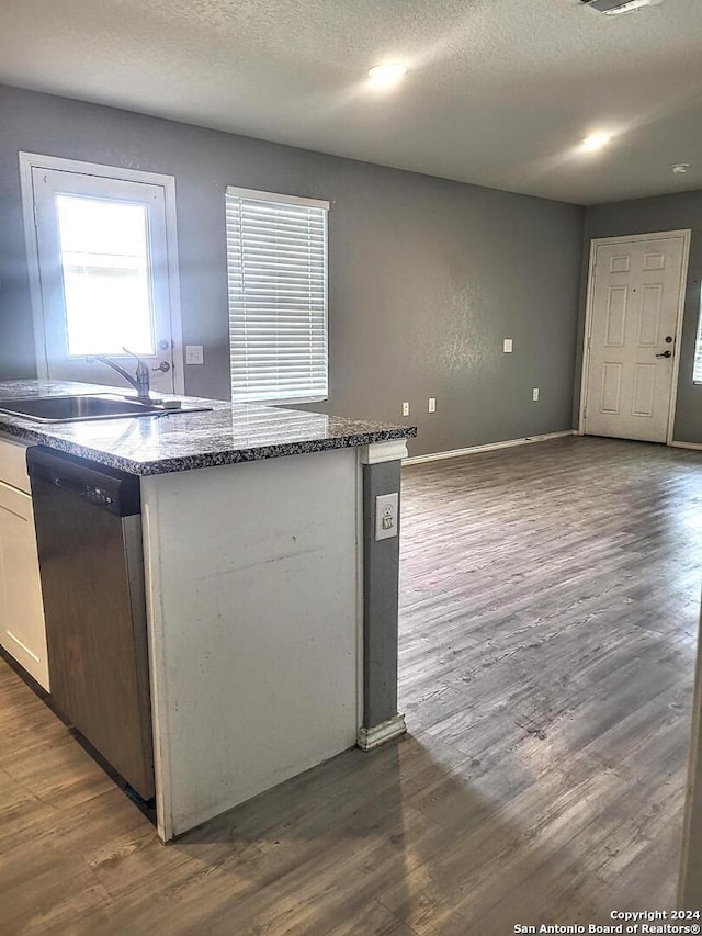 kitchen featuring white cabinetry, sink, stainless steel dishwasher, dark hardwood / wood-style floors, and a textured ceiling