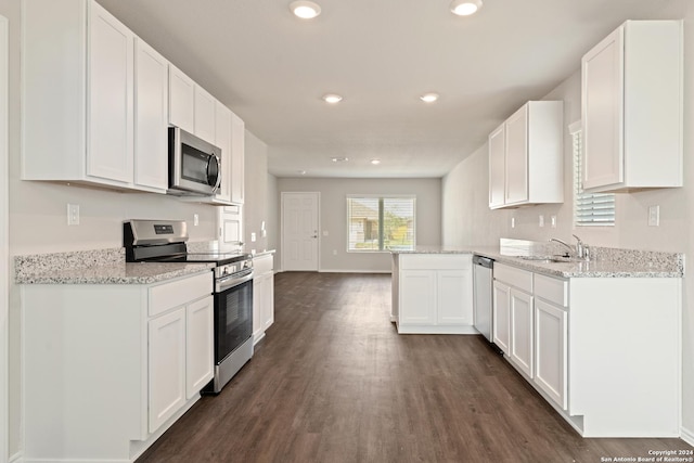 kitchen featuring white cabinets, sink, light stone countertops, appliances with stainless steel finishes, and kitchen peninsula