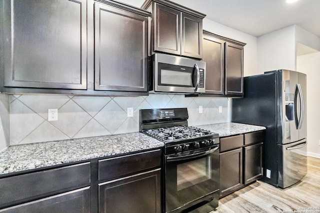 kitchen with light stone countertops, appliances with stainless steel finishes, light wood-type flooring, backsplash, and dark brown cabinetry