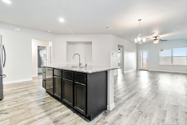 kitchen with pendant lighting, a kitchen island with sink, sink, light stone countertops, and appliances with stainless steel finishes