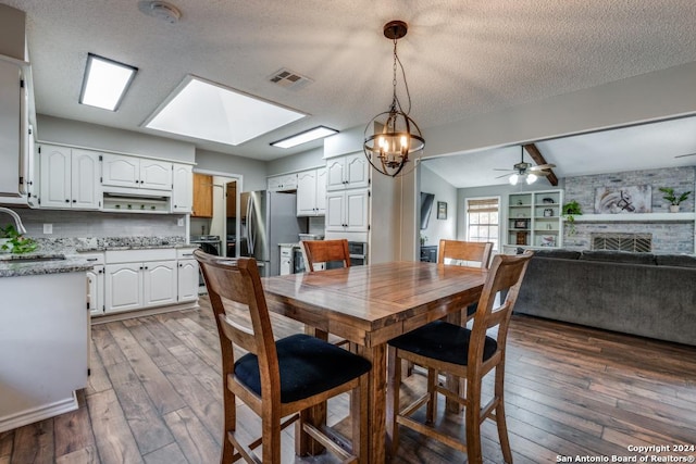 dining space featuring dark hardwood / wood-style flooring, a textured ceiling, ceiling fan, sink, and a fireplace